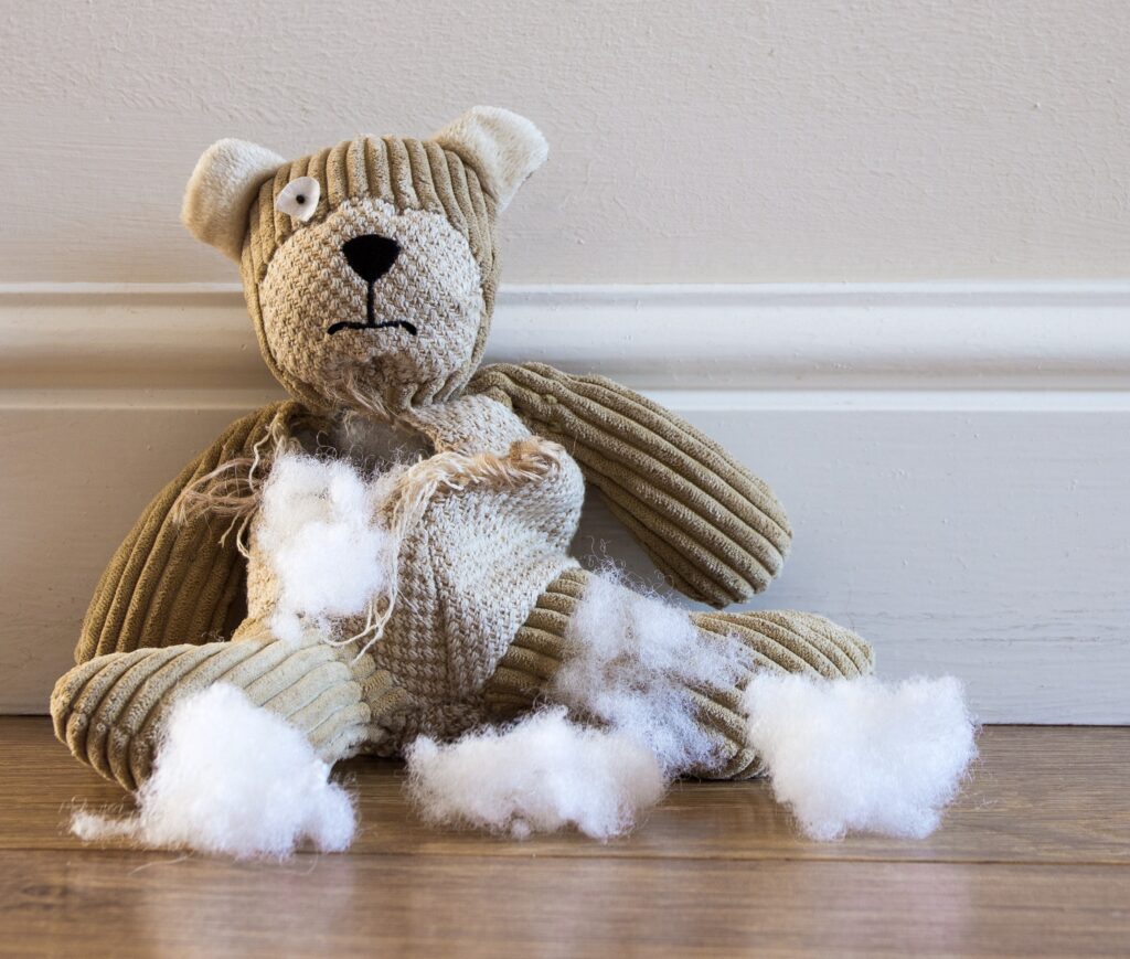 torn teddy bear sitting on floor