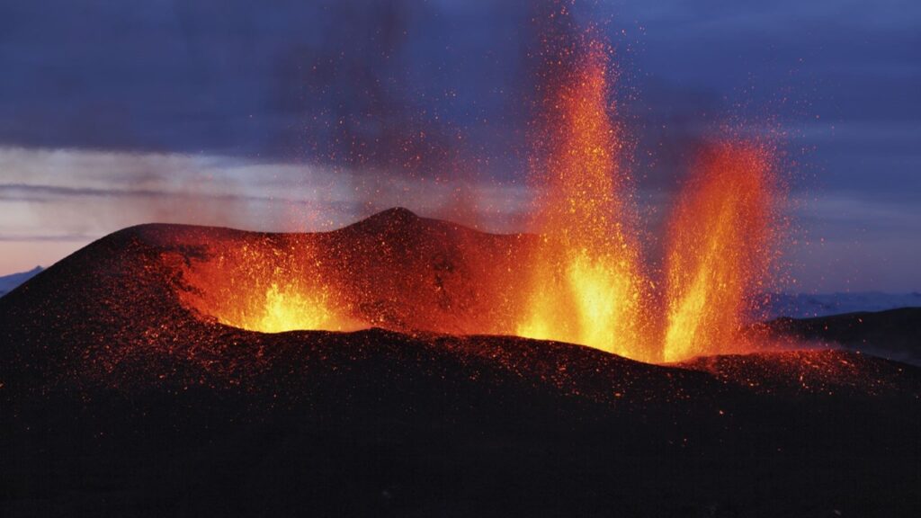 Volcano erupting against dark blue background