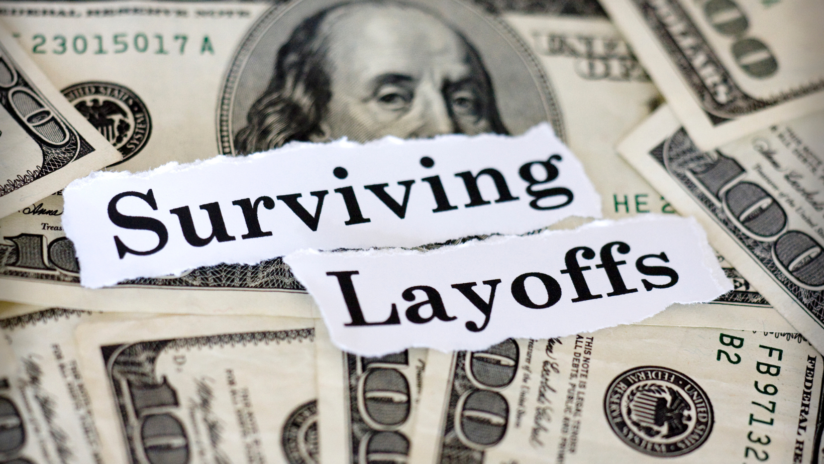 sign reading surviving layoffs on top of US bills