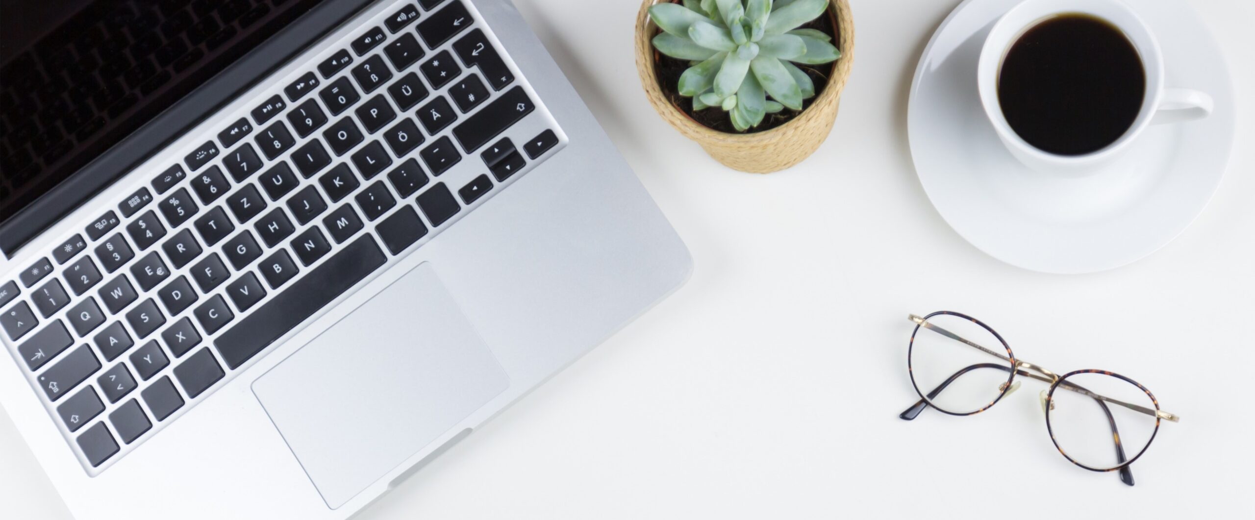 white desk with laptop, glasses, succulent plant and white coffee cup